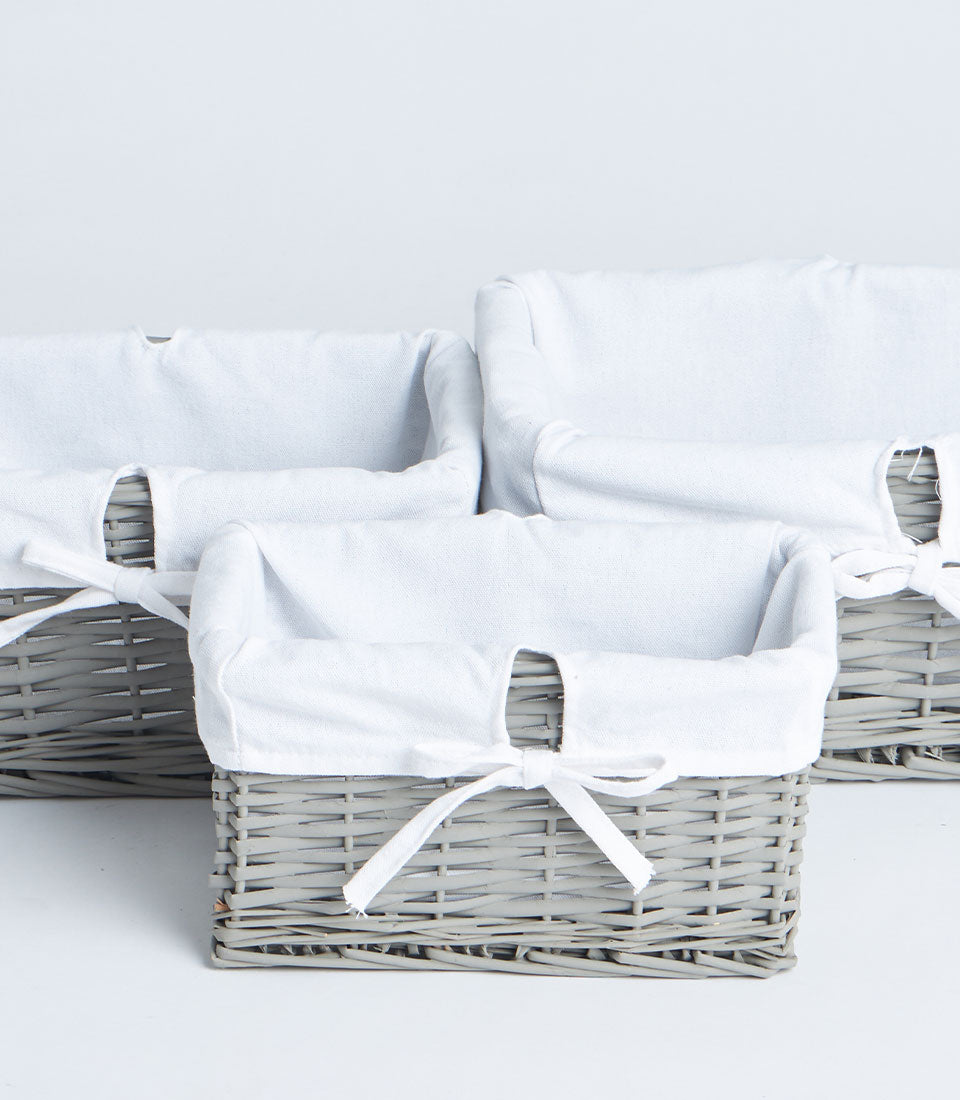 Handwoven light grey wicker baskets with removable white fabric liners and ribbon detail