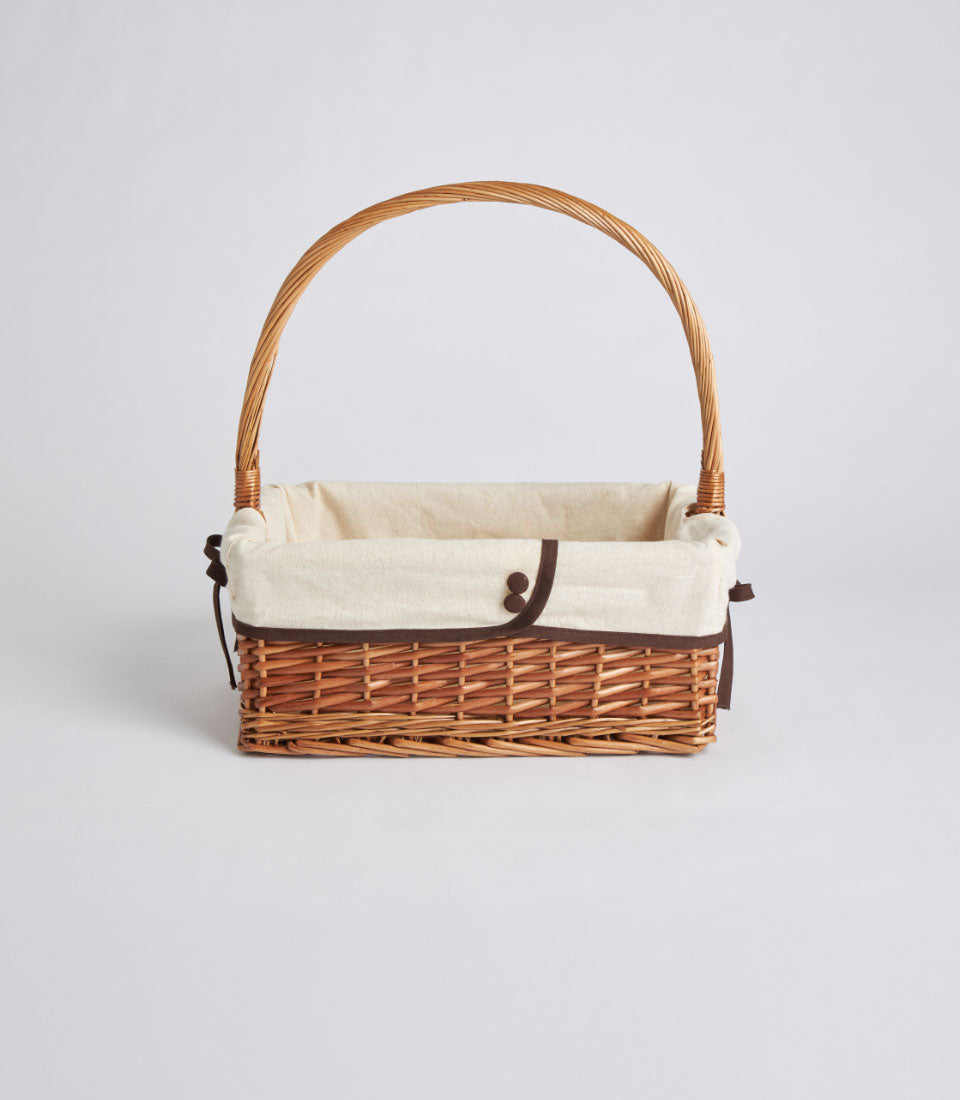 Natural woven rectangular wicker gift basket with cream fabric lining and brown ribbon detail