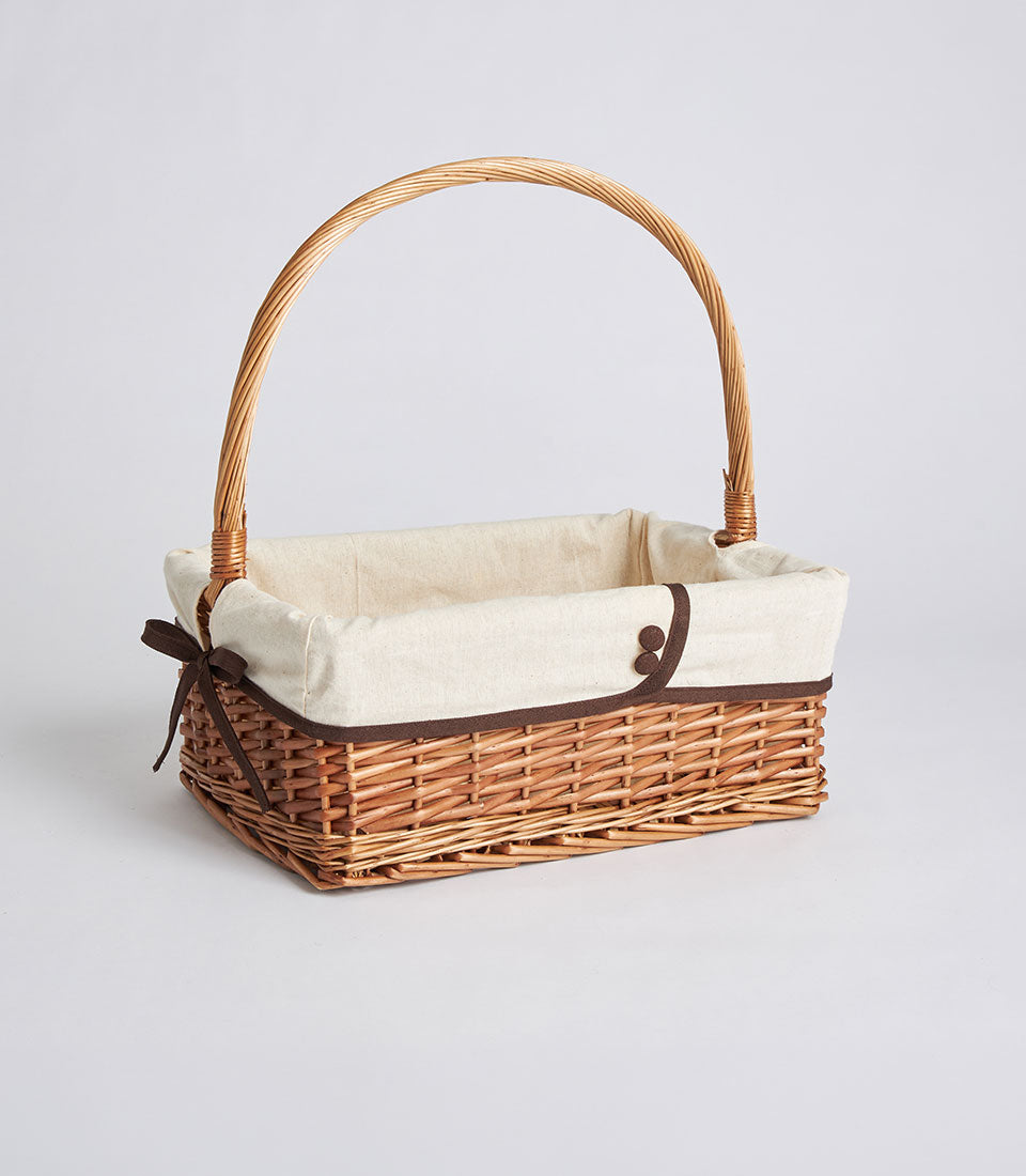 Handwoven rectangular wicker basket with cream fabric liner and dark brown ribbon bow