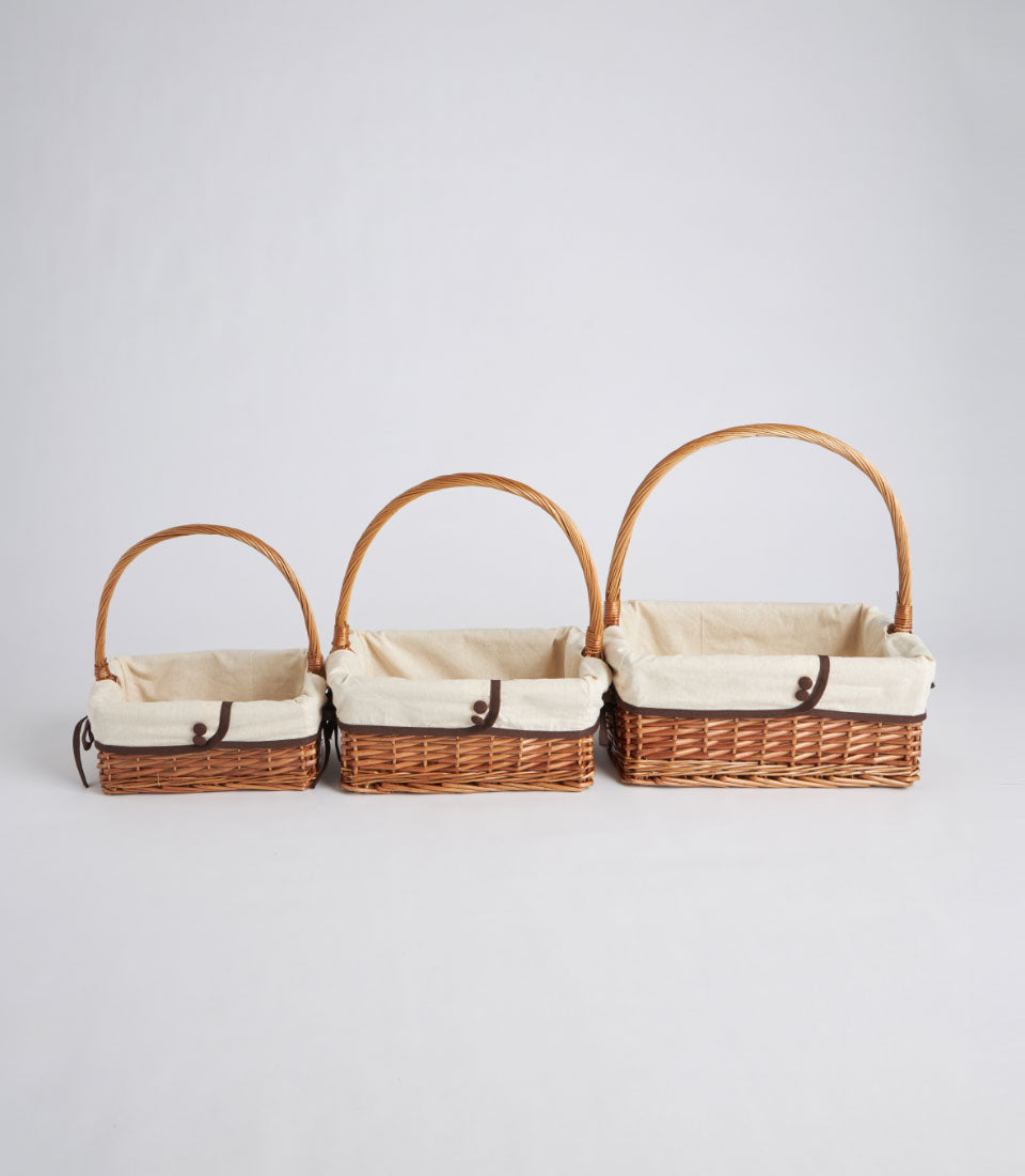 Handwoven wicker baskets with cream fabric liners and handles in three sizes for luxury gifting