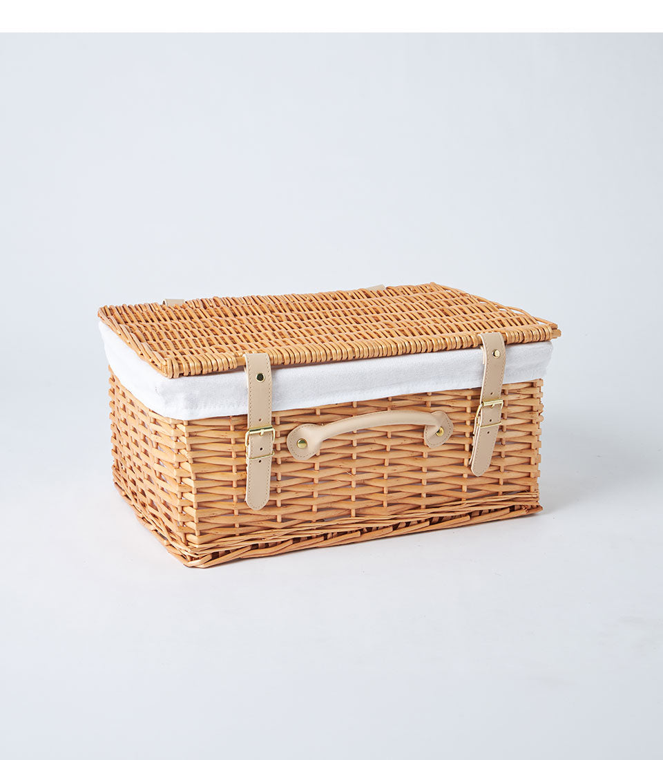 Handwoven light brown wicker picnic basket with leather straps and gold buckle closures