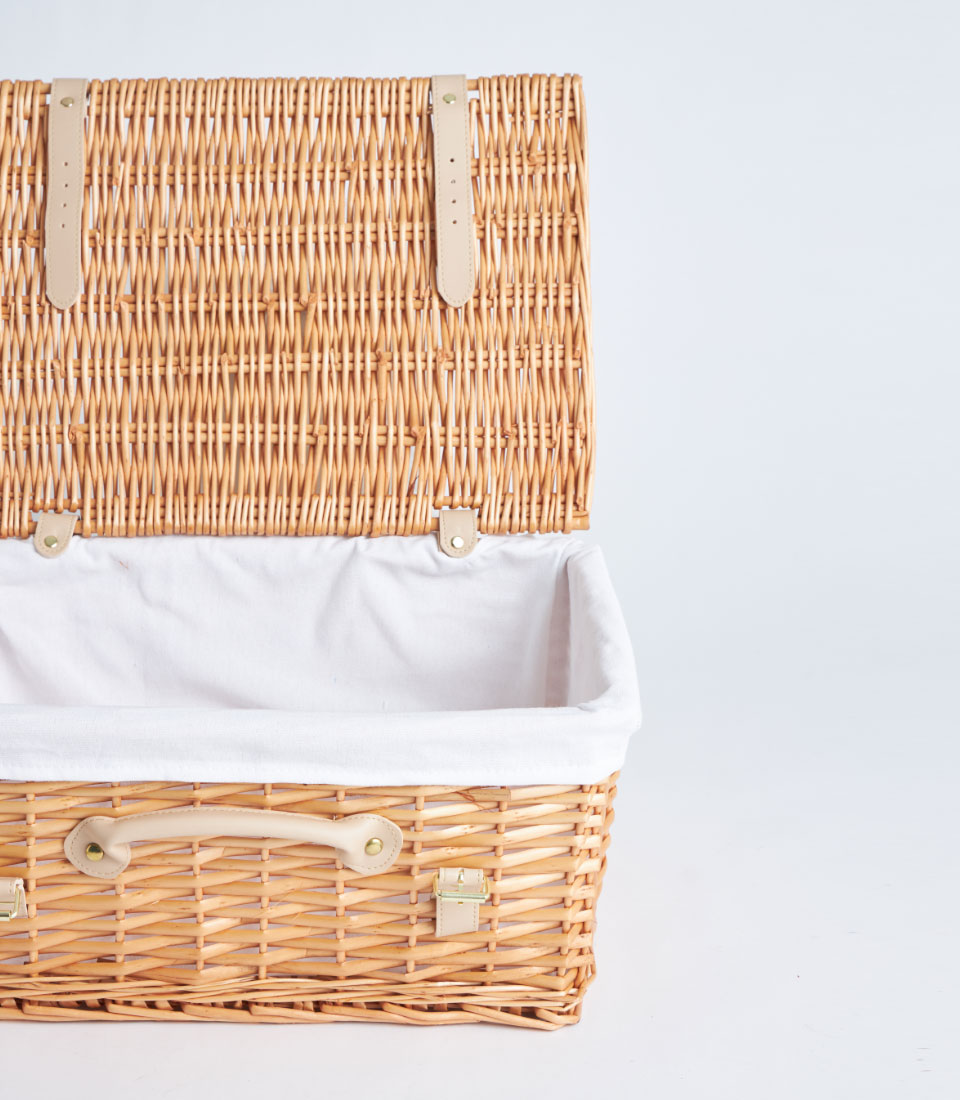 Light brown handwoven picnic basket with white linen lining and faux leather straps, gold hardware