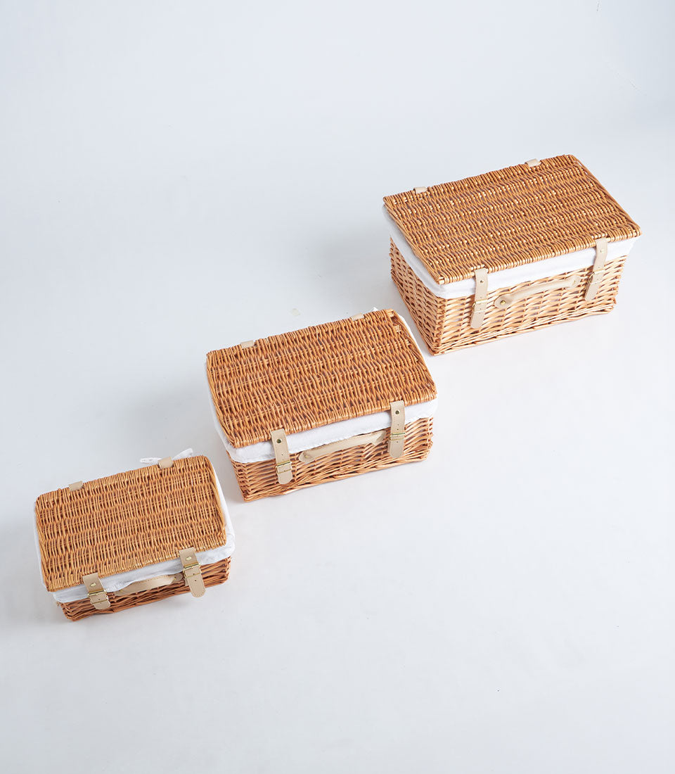 Handwoven light brown wicker picnic baskets with leather straps in three sizes for gourmet gifting