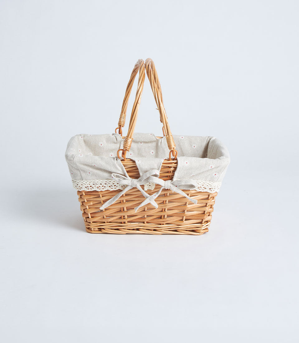 Light brown handwoven wicker basket with grey floral fabric lining and white lace trim