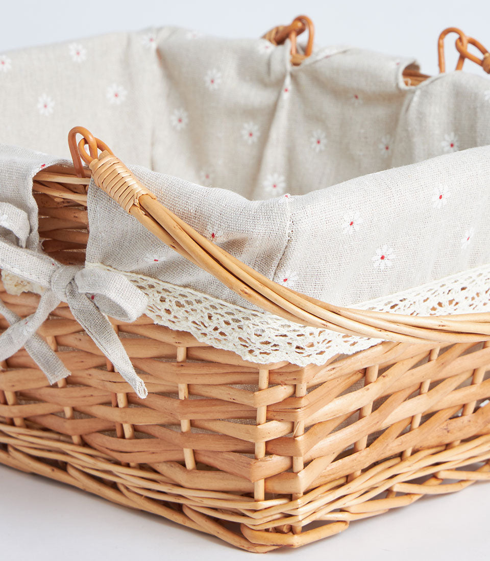 Handwoven rectangular wicker basket with beige floral fabric liner and white lace trim