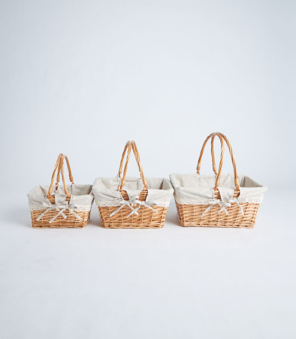 Handwoven wicker baskets with beige fabric linings, white lace trim, and ribbon bows in graduated sizes