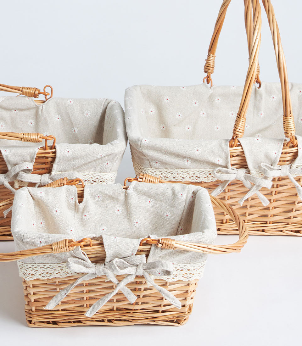 Three handwoven wicker baskets with fabric liners, lace trim, and beige daisy-print fabric bows