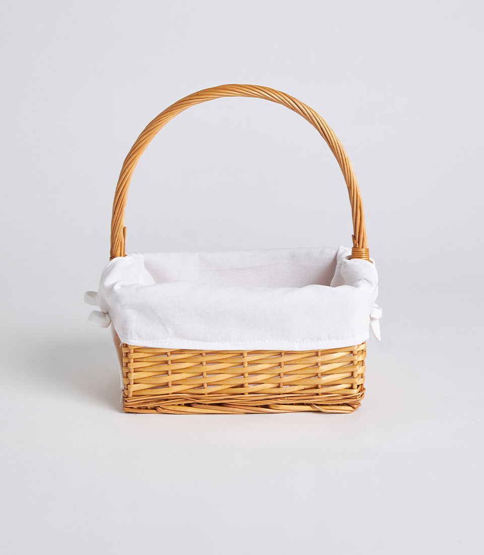 Light brown woven rattan rectangular basket with white fabric liner and tall arched handle