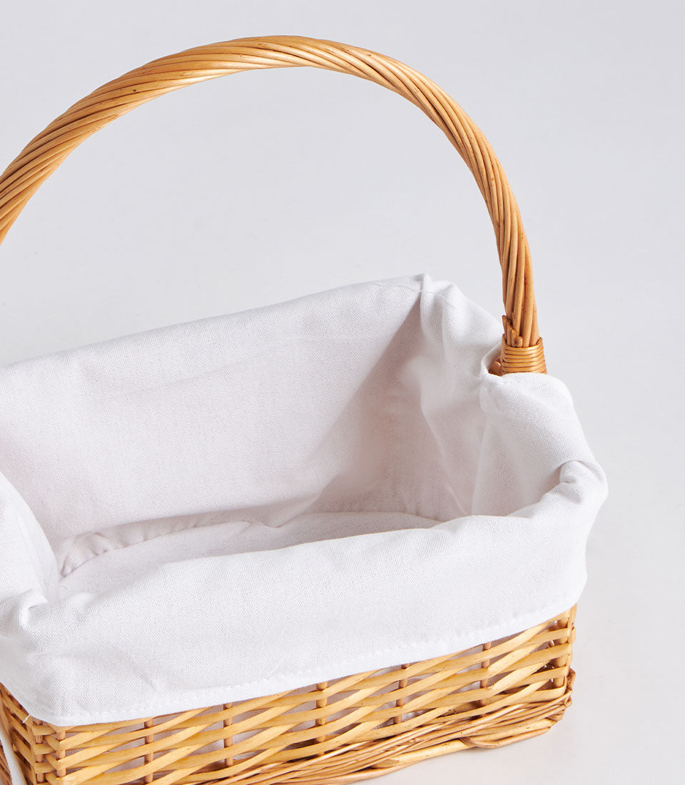 Light brown handwoven wicker basket with tall handle and white fabric lining
