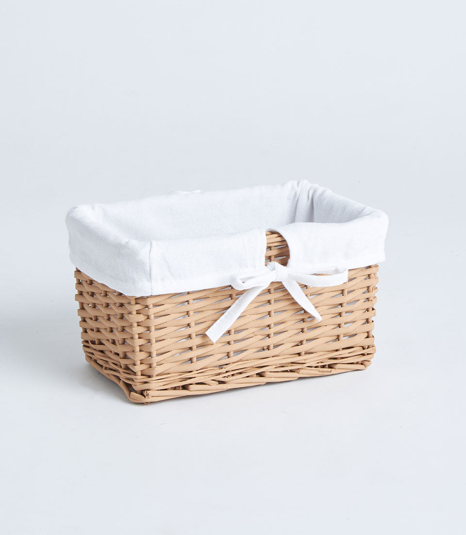 Light brown wicker rectangular basket with white fabric lining and ribbon bow
