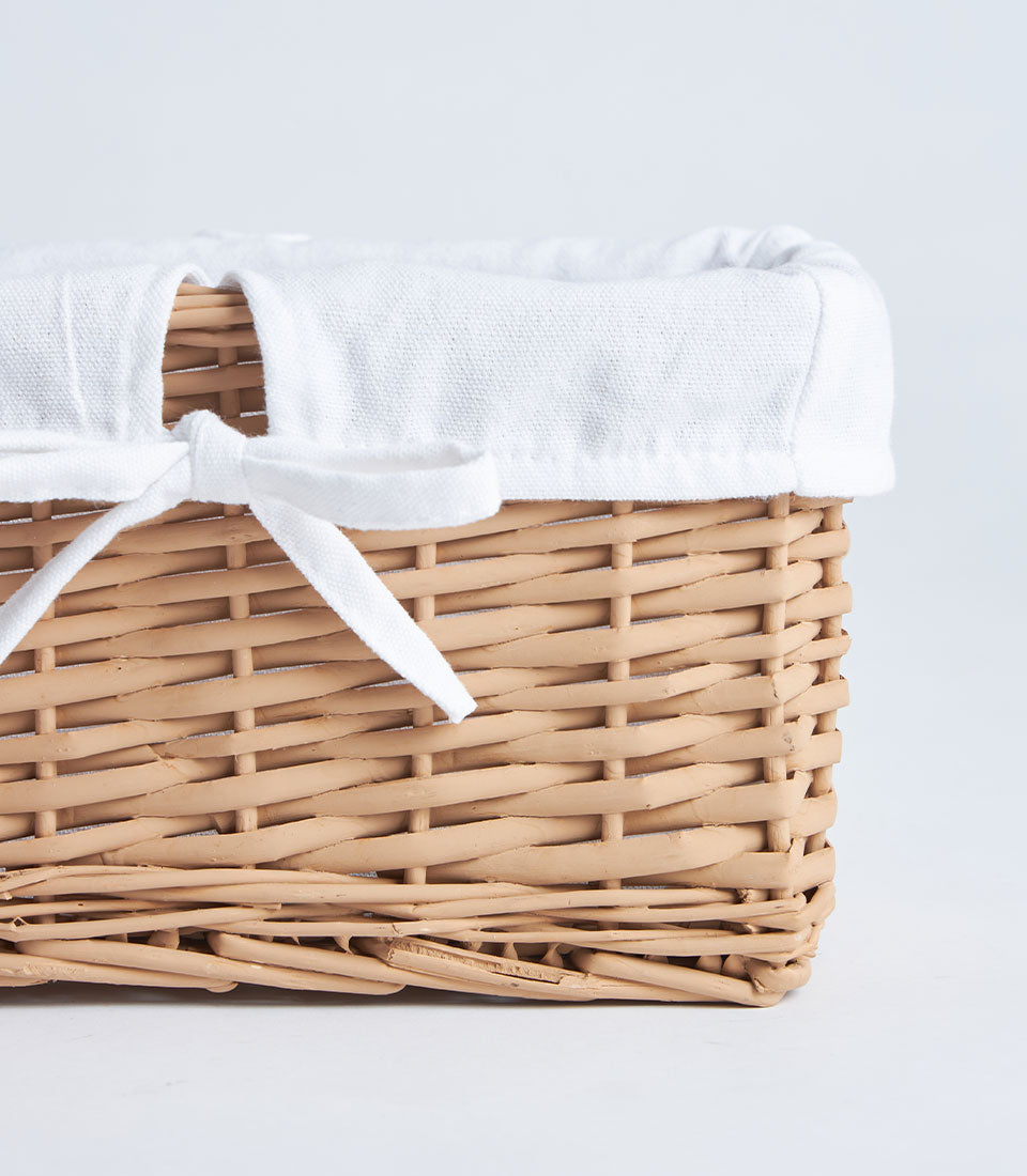 Natural wicker rectangular basket with white fabric lining and ribbon bow