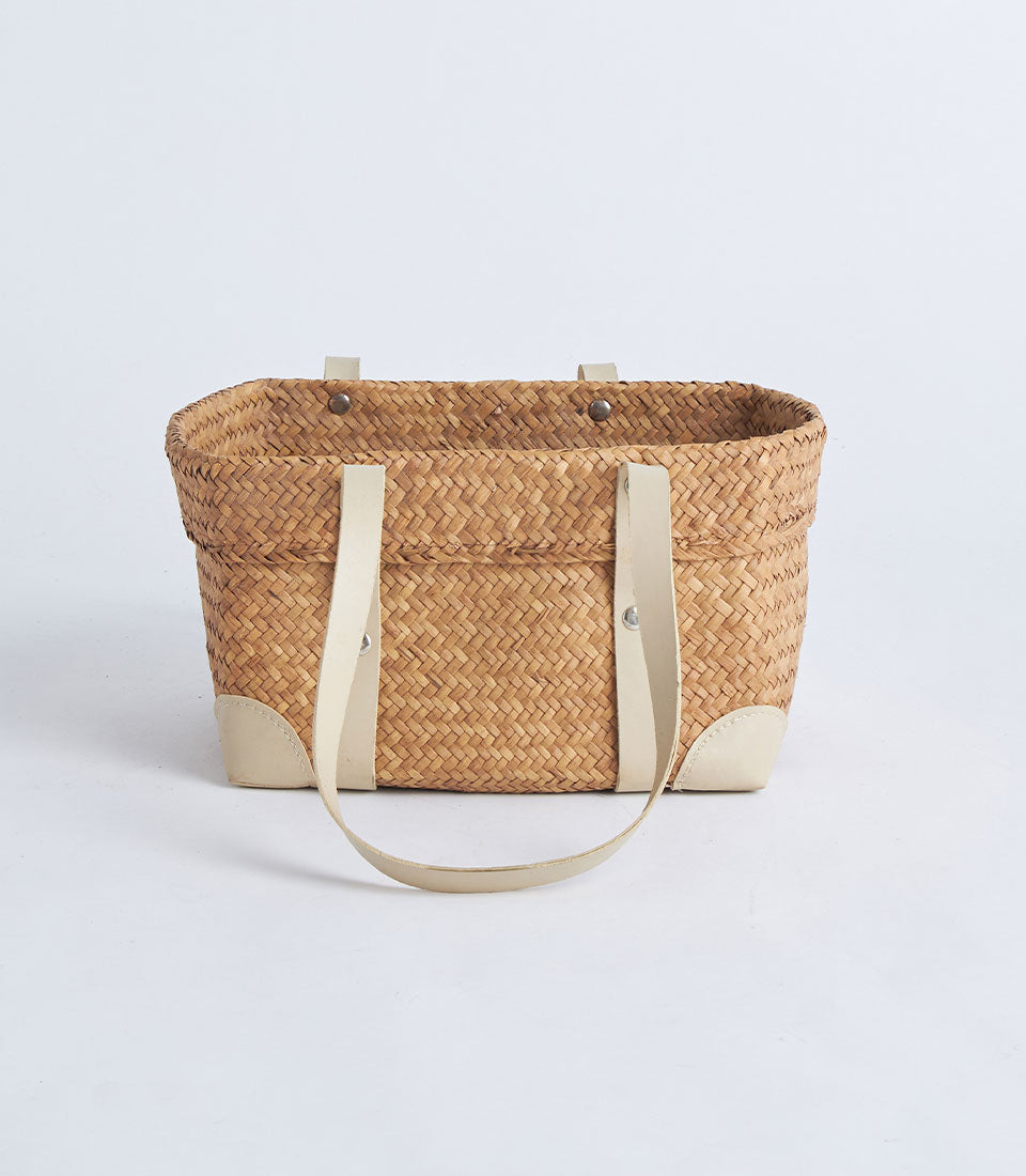 Natural woven straw basket with leather handles and reinforced corners
