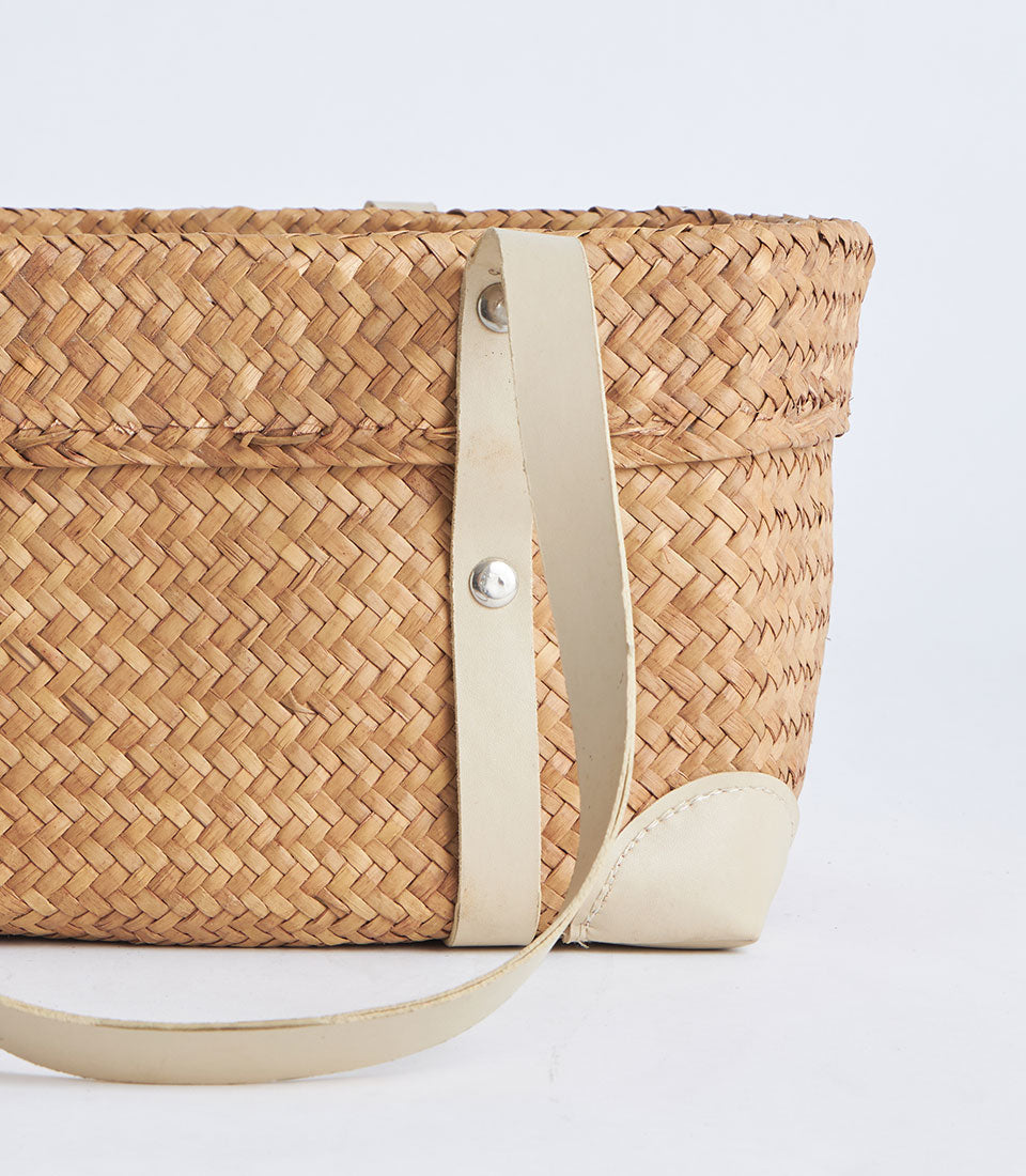 Natural woven straw basket with leather strap handles and reinforced corners