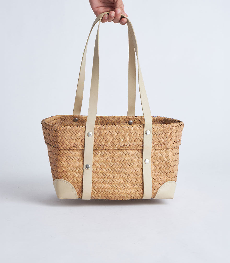 Natural woven straw basket with leather handles and reinforced corners