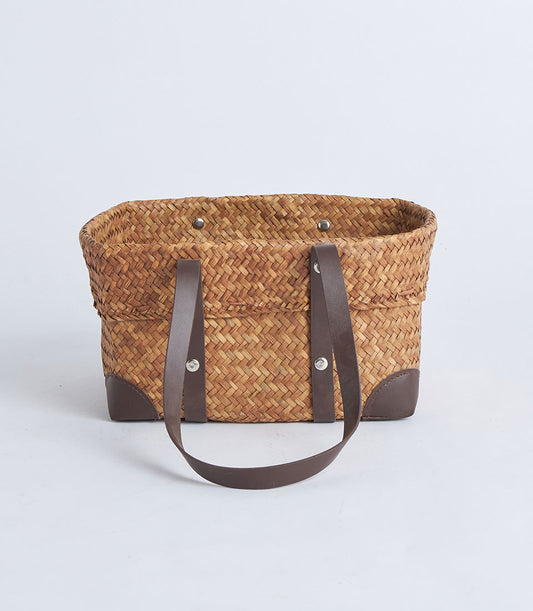 Natural woven straw basket with black leather handles and silver rivets