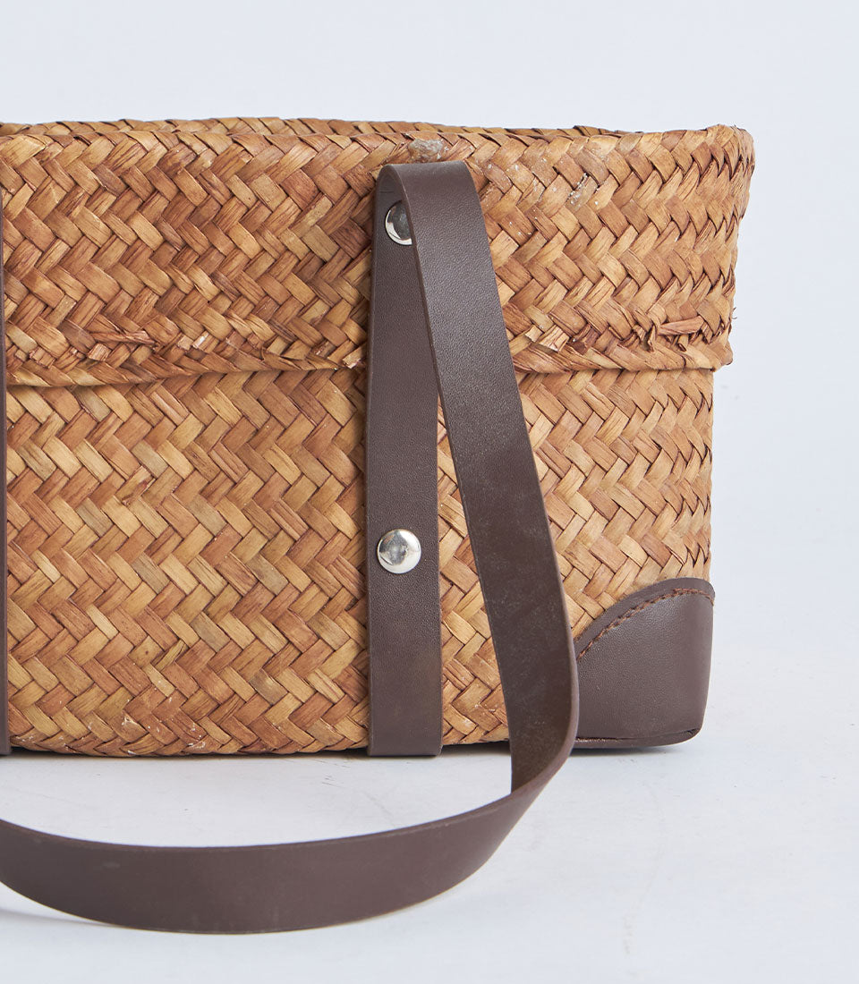 Natural woven oval basket with black leather strap handles and silver rivets