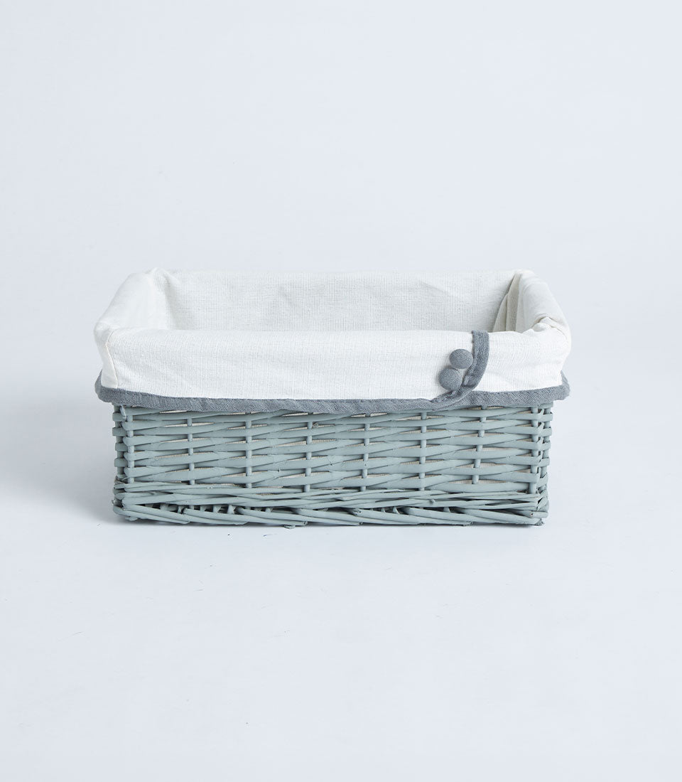 Light grey-blue handwoven wicker basket with white fabric liner and decorative grey trim buttons