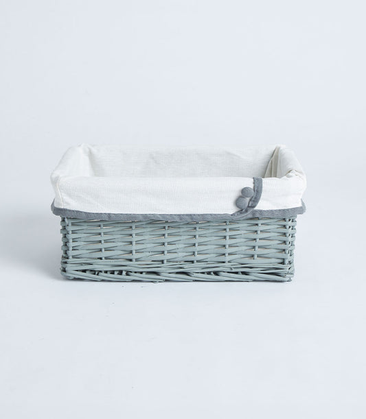 Light grey-blue handwoven wicker basket with white fabric liner and decorative grey trim buttons