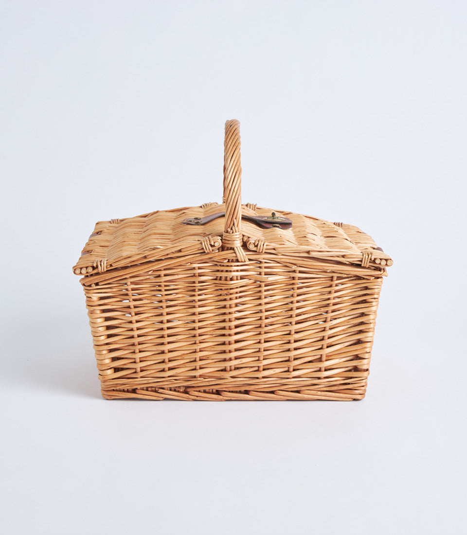 Light brown handwoven wicker picnic basket with leather straps and metal buckles