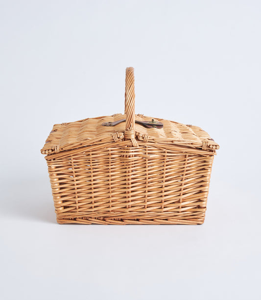 Light brown handwoven wicker picnic basket with leather straps and metal buckles