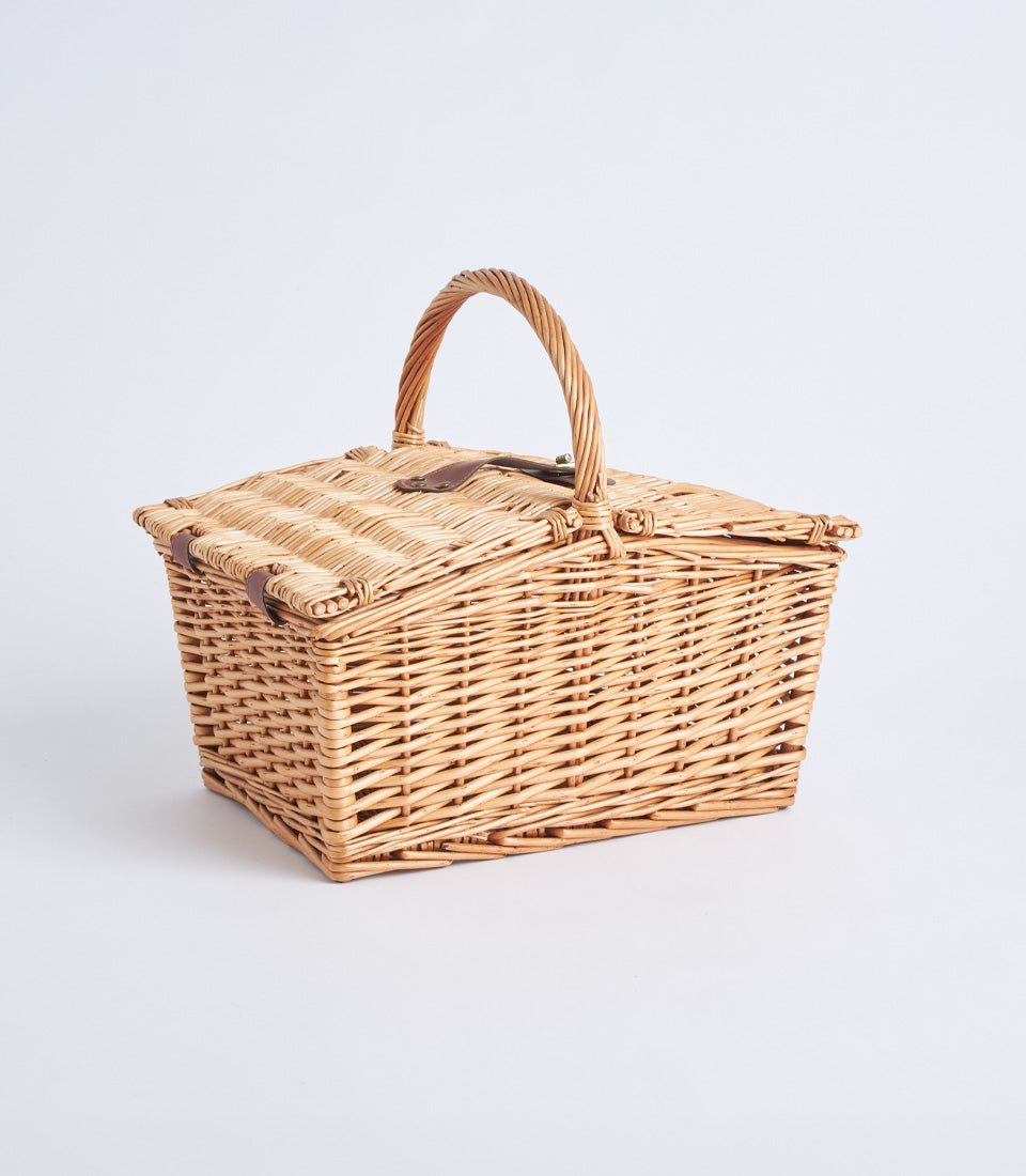 Light brown handwoven wicker picnic basket with leather straps and hinged lid