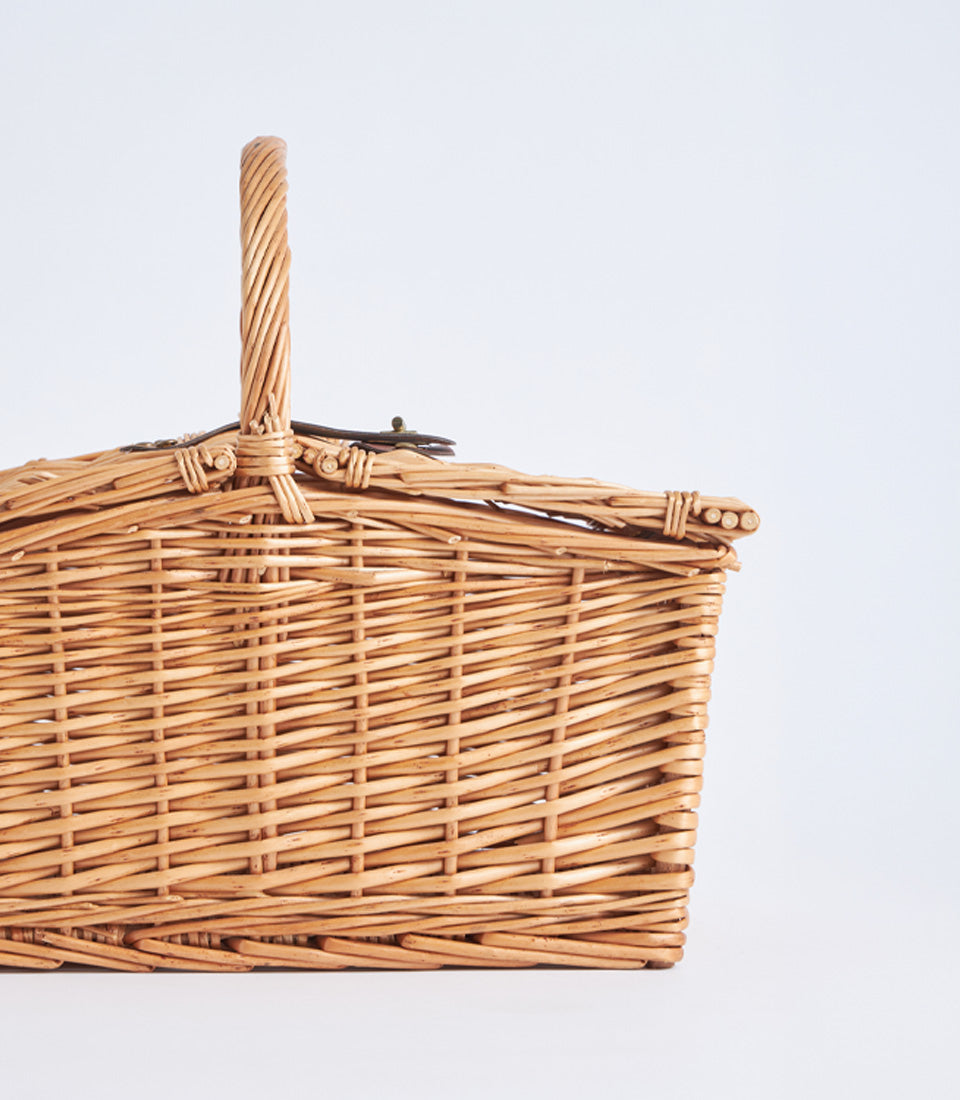 Light brown handwoven wicker picnic basket with metal clasp lid and twisted handle