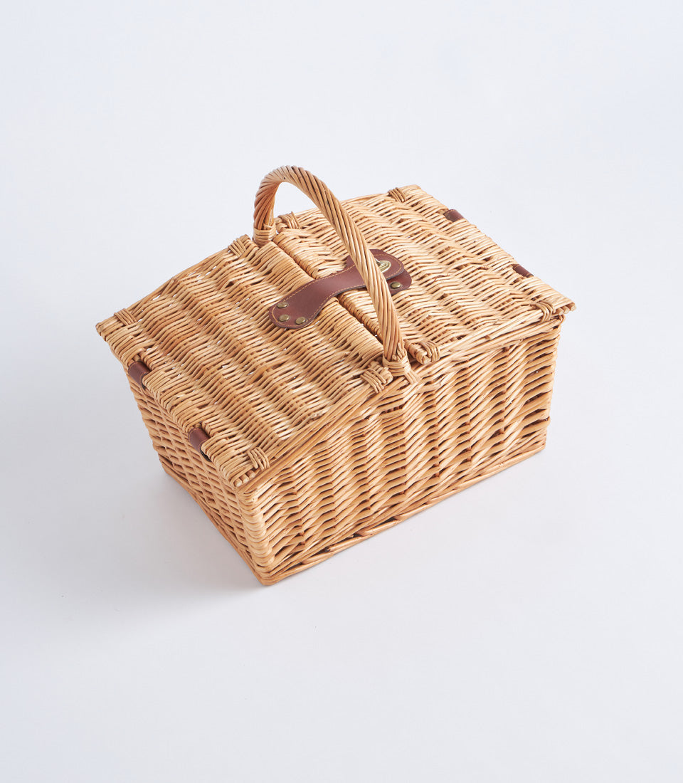 Handwoven light brown wicker picnic basket with leather straps and brass hardware