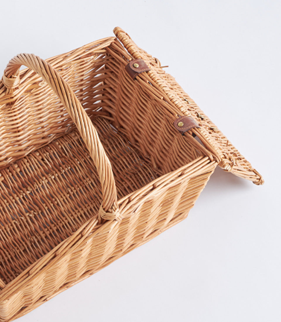Light brown handwoven wicker picnic basket with leather straps and brass studs