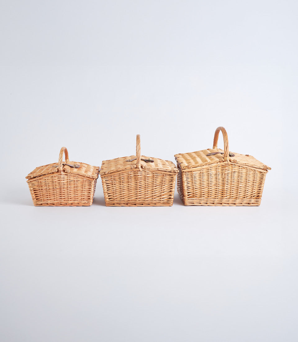 Handwoven light brown wicker picnic baskets with hinged lids and leather closures, set of three sizes