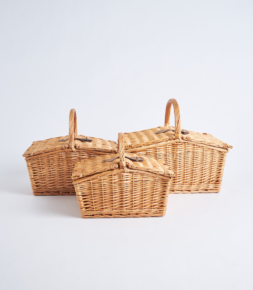 Natural wicker picnic baskets with leather straps and hinged lids in graduated sizes