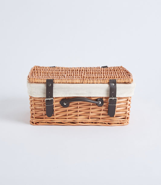 Handwoven light brown wicker picnic basket with cream linen interior and dark leather straps