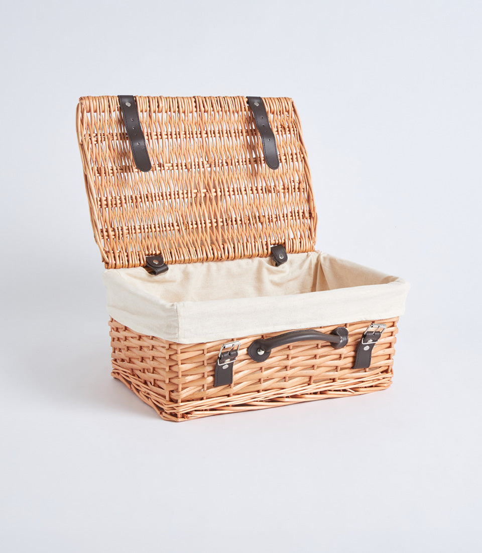 Handwoven light brown wicker picnic basket with cream linen interior and leather straps