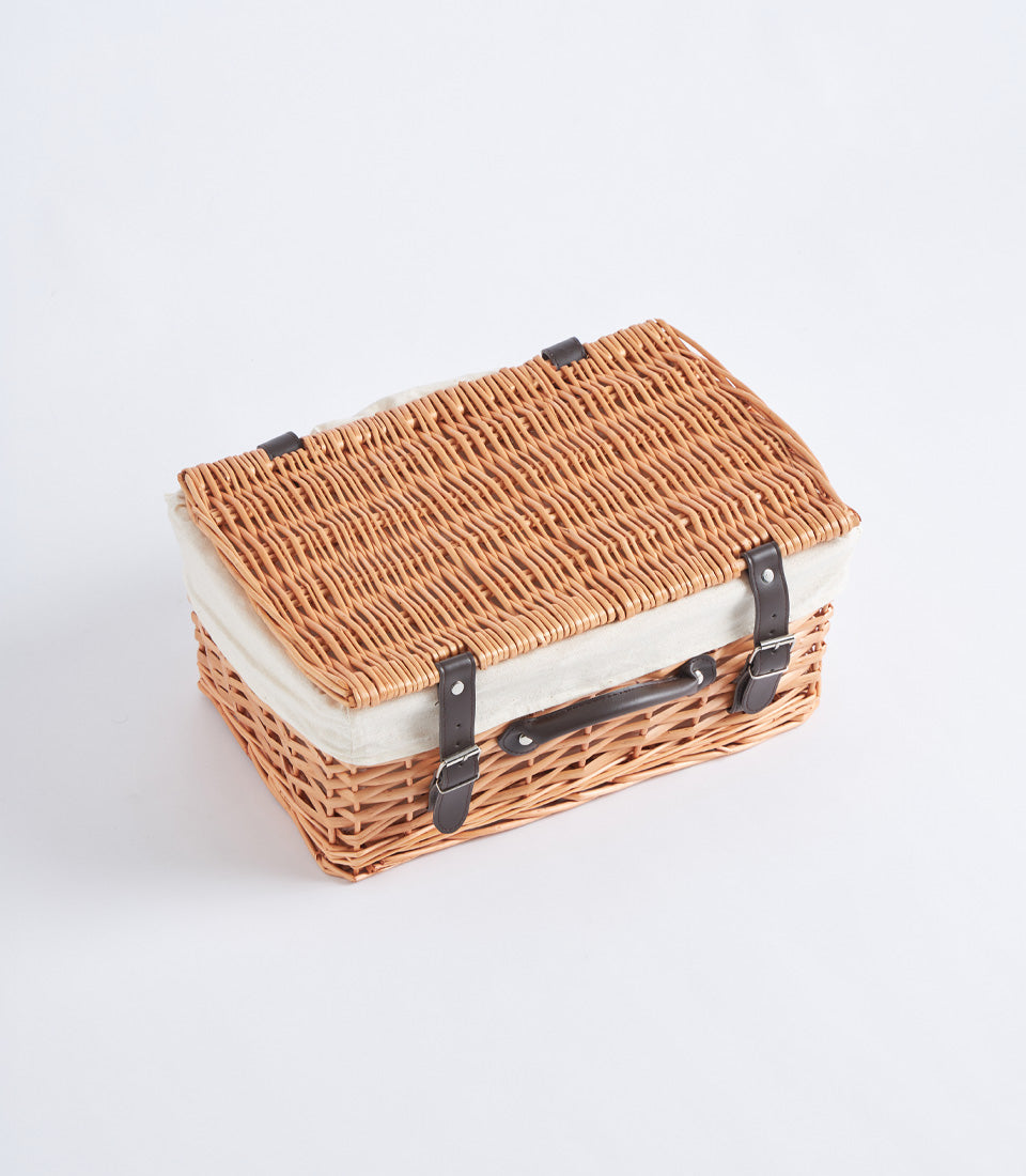 Handwoven light brown wicker picnic basket with cream linen lining and dark leather straps
