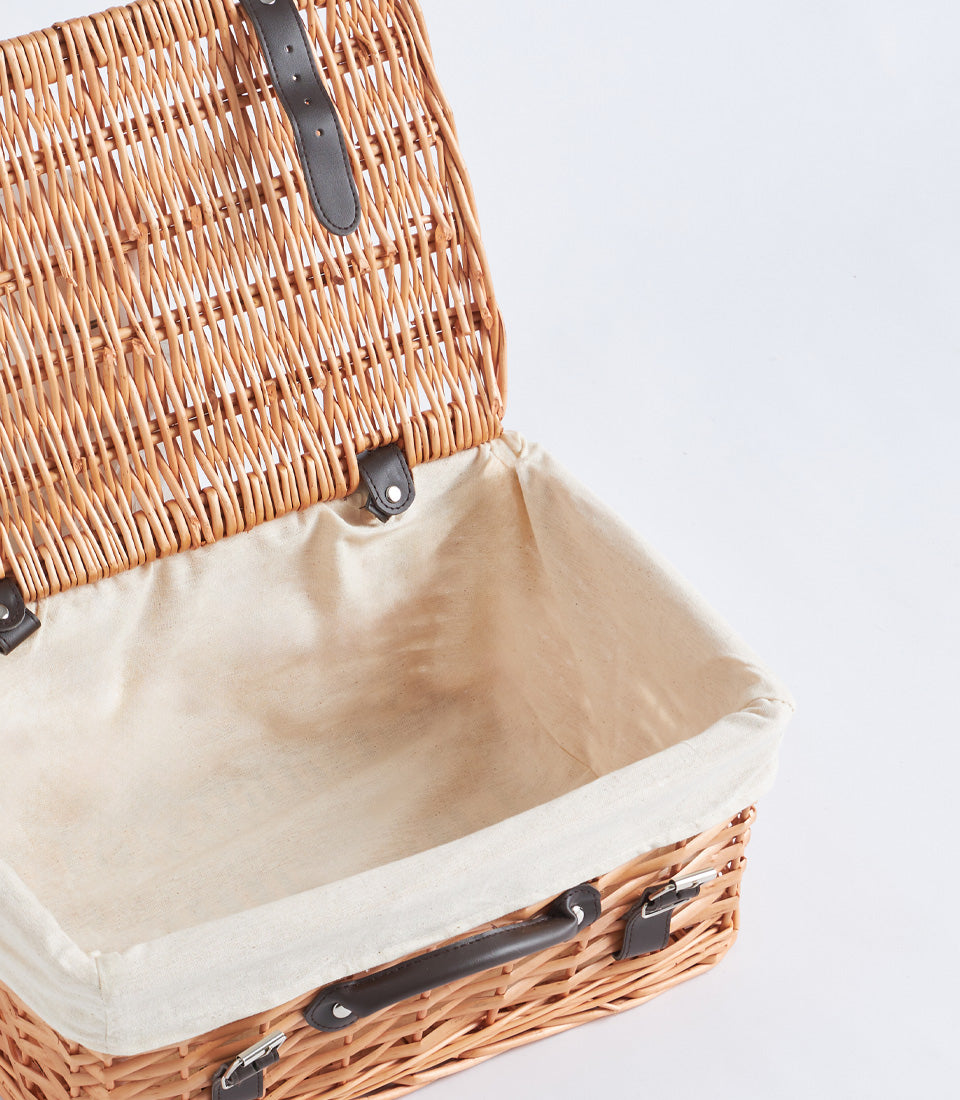 Light brown handwoven wicker picnic basket with leather straps and cream fabric lining