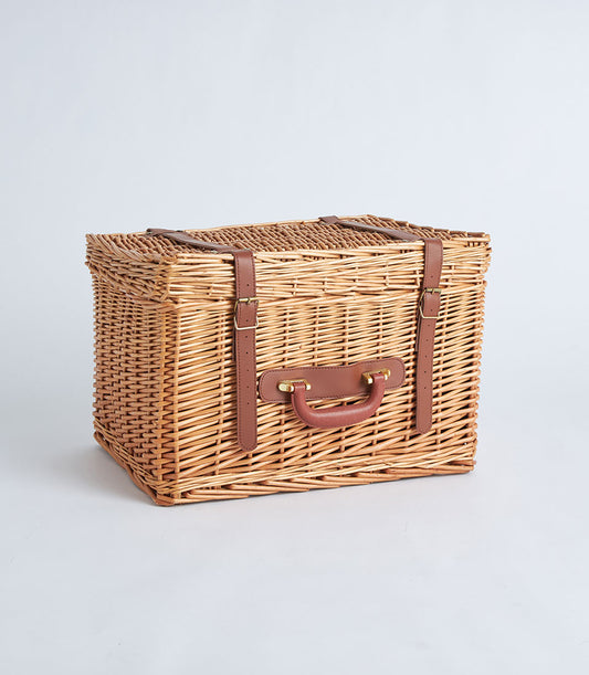 Natural wicker suitcase basket with dark brown leather straps and gold buckle hardware
