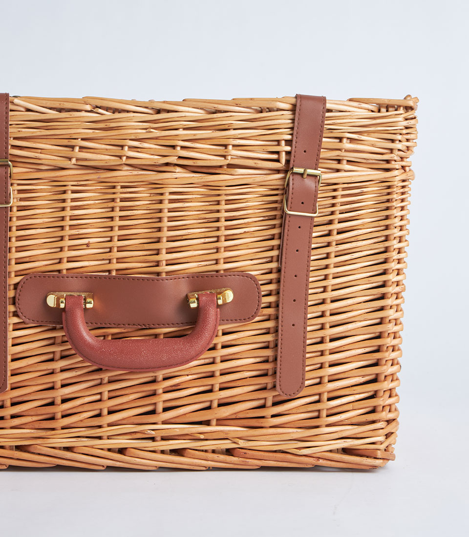 Natural wicker suitcase basket with leather straps and gold buckle closure