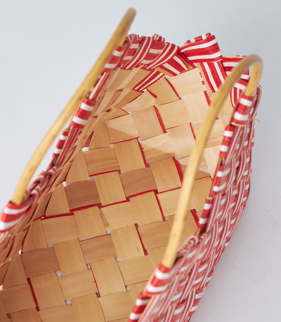 Red patterned fabric-wrapped woven gift basket with wooden handles and light brown weave