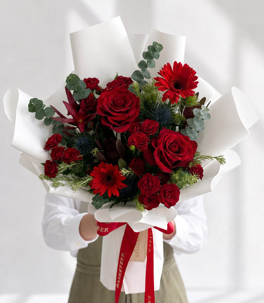 A vibrant Basketeer luxury gift bouquet featuring lush red roses, cheerful ger