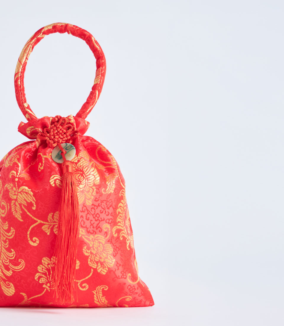 Red silk brocade gift pouch with gold floral embroidery, handle, and tassel closure