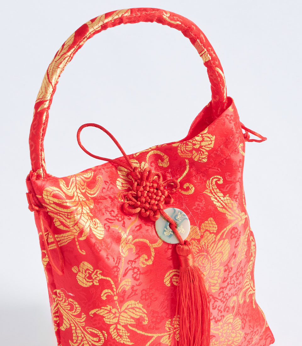 Red brocade gift basket with gold floral patterns, tassel and decorative coin charm