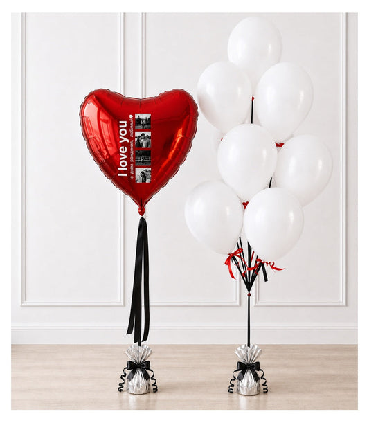 Red heart-shaped "I love you" foil balloon with photo frame and white balloons with red ribbons on weighted bases.