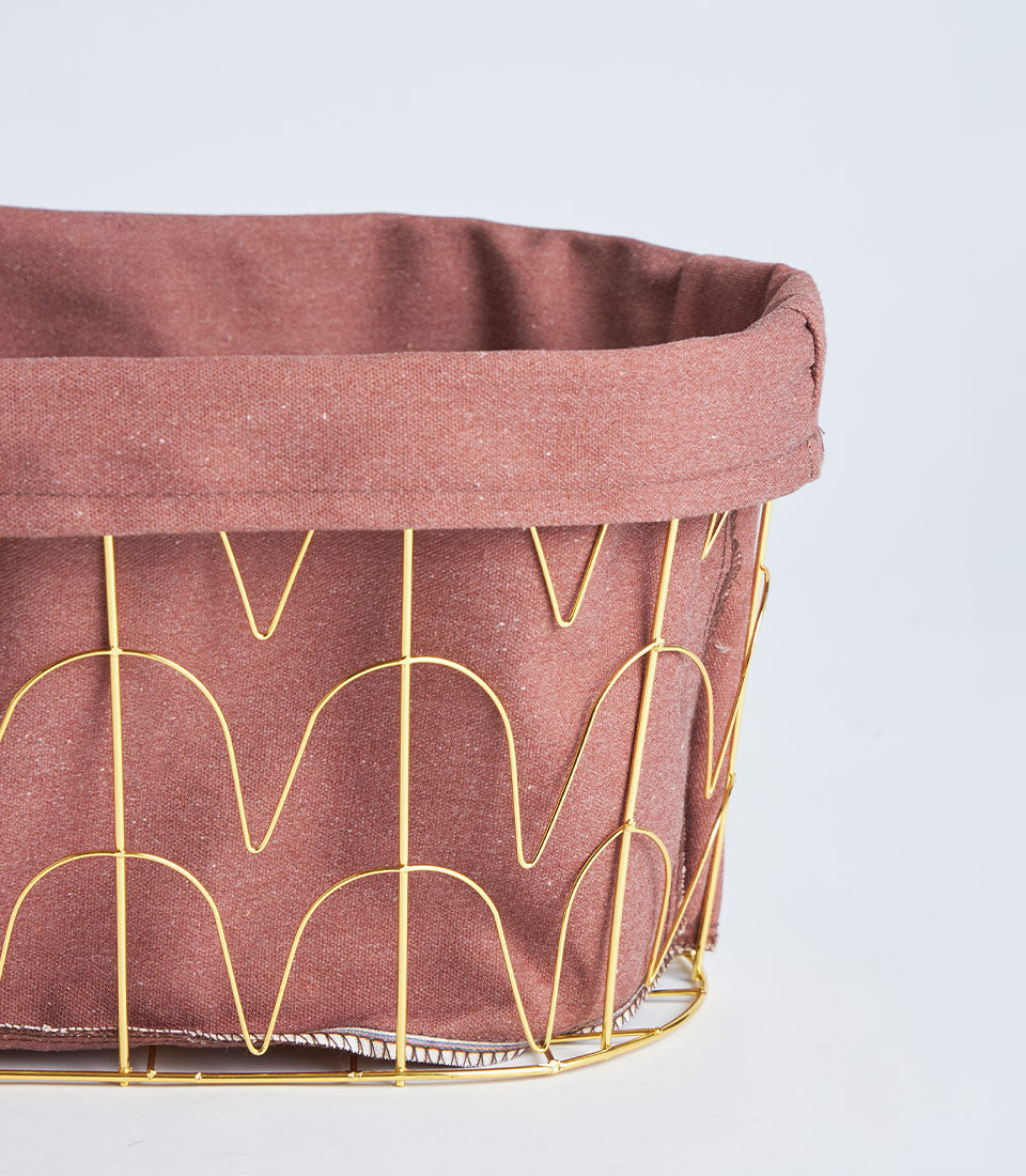 Round metal basket with tall gold handles and dusty rose fabric lining, perfect for luxury gift hampers
