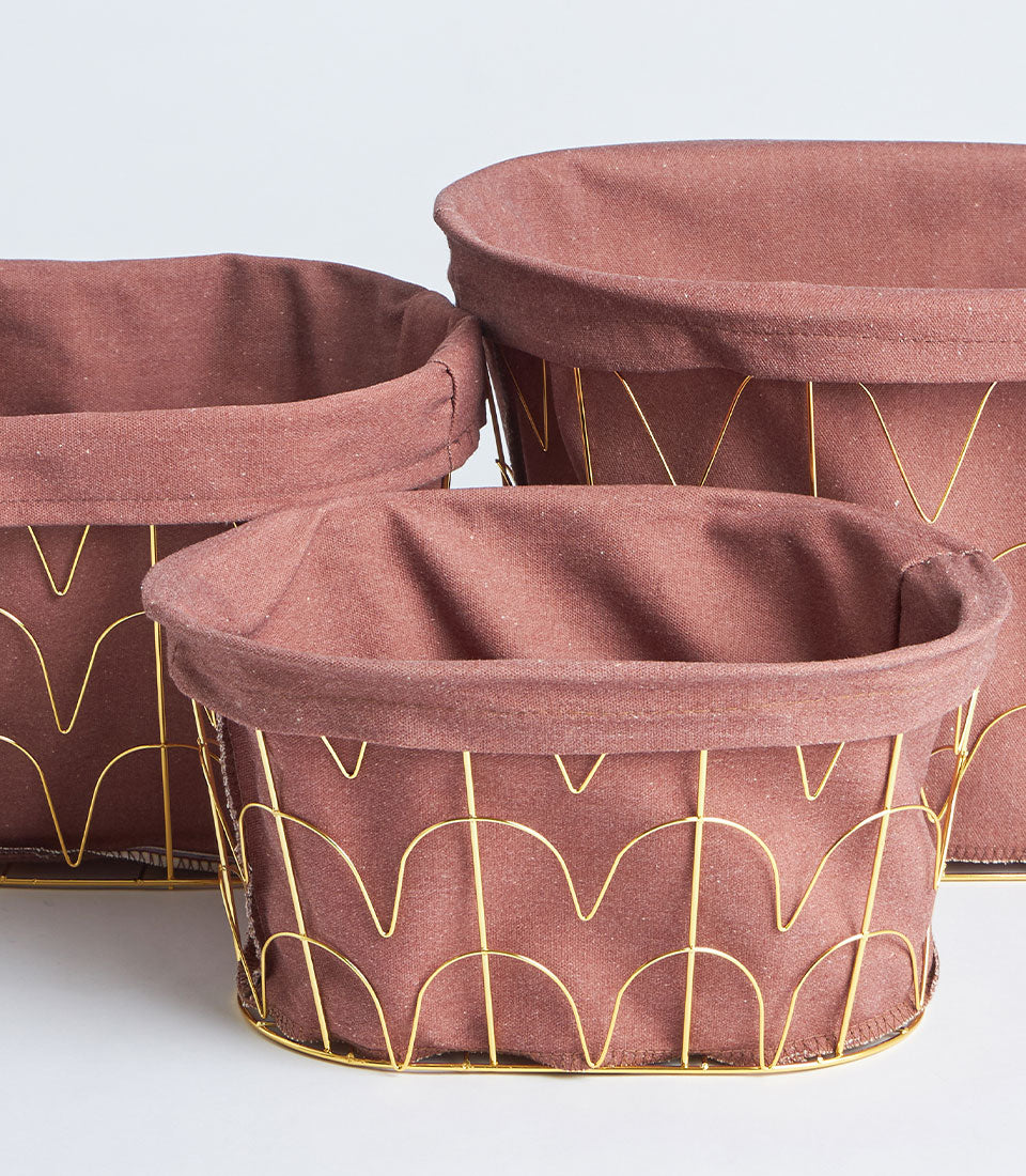 Round metal frame baskets with tall gold handles and dusty rose fabric linings, stacked in three sizes for versatile storage