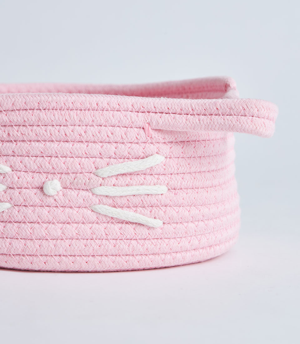 Pink woven rope storage basket with playful cat face design and handles