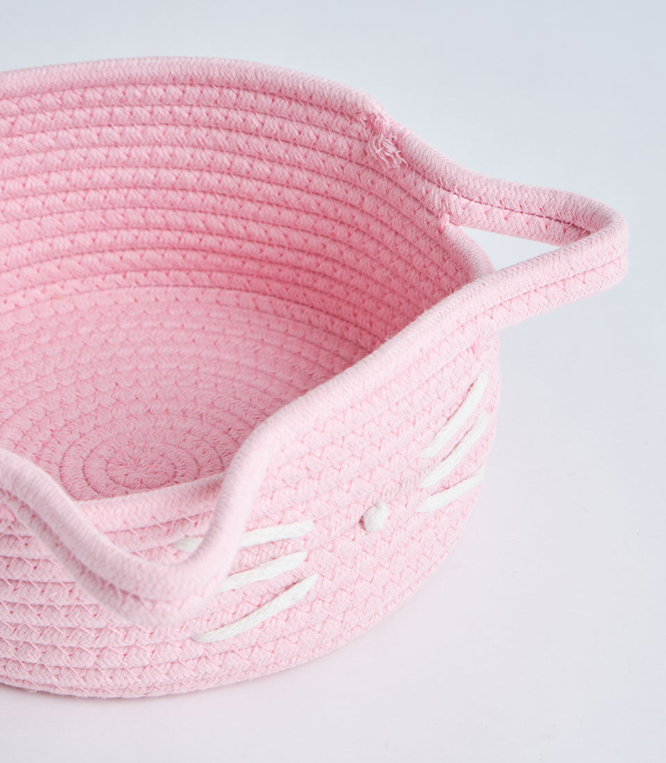 Light pink woven cotton rope basket with playful cat-face design and handles