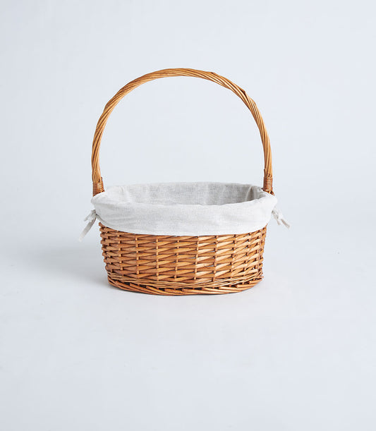 Handwoven light brown wicker oval basket with arched handle and soft grey fabric liner