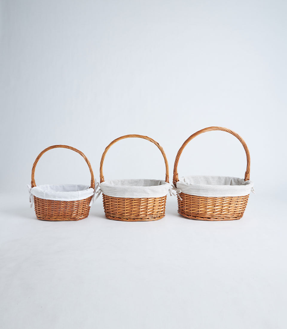 Handwoven wicker baskets with fabric liners in three graduating sizes, light brown willow with grey linen inserts and tie