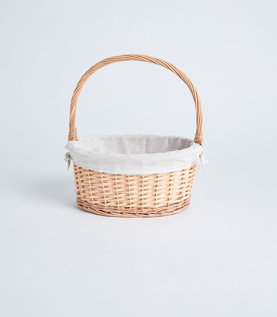 Natural woven wicker gift basket with beige fabric liner and arched handle