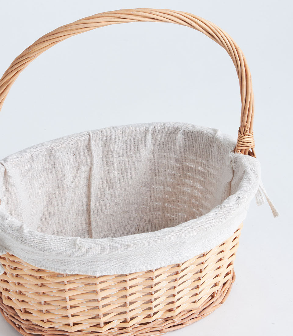 Light oval wicker gift basket with beige fabric liner and woven handle