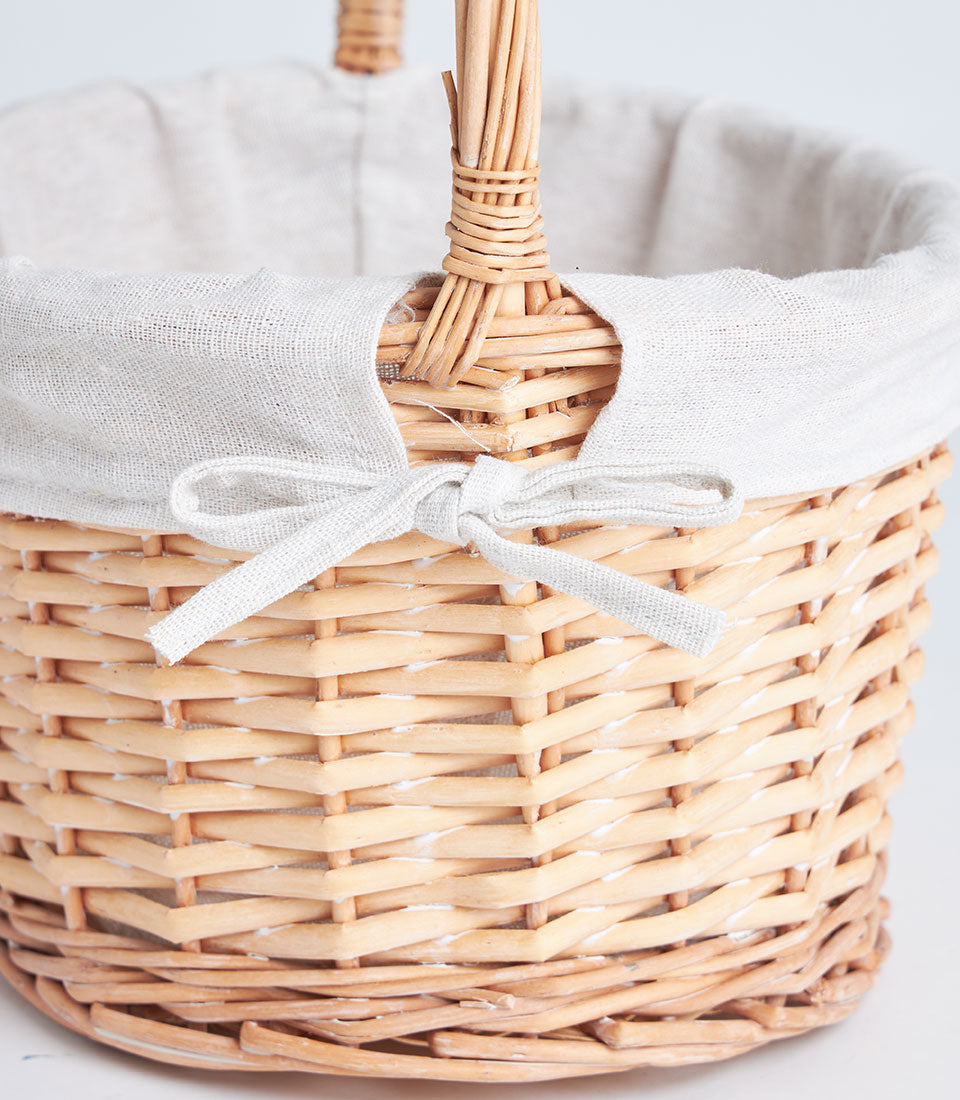 Natural wicker gift basket with cream fabric liner and woven handle